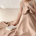 Woman reading under beige cotton blanket with textured muslin weave