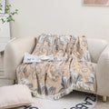 Beige cotton couch throw blanket with tassels, jacquard floral design styled on sofa with book