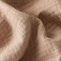 Close-up of soft beige cotton muslin blanket with crinkle texture

