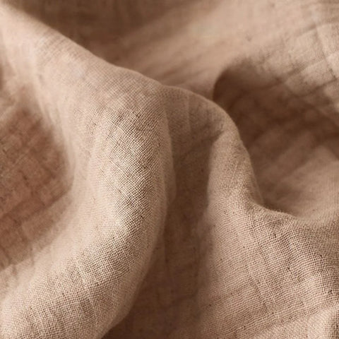 Close-up of soft beige cotton muslin blanket with crinkle texture

