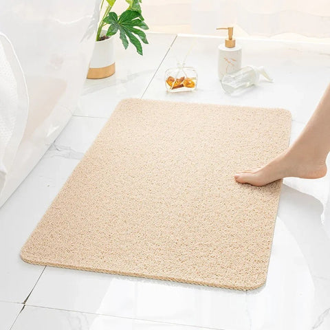 Beige bath mat on a bathroom floor with a foot stepping onto it