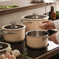 Two beige stainless steel pots on kitchen stove beside eggs