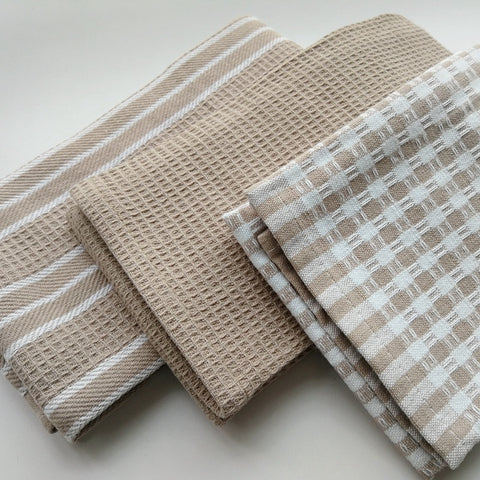 Set of four beige and white patterned towels on a light background
