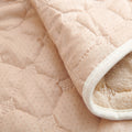 Close-up of a beige quilted fabric with white trim recliner slipcover