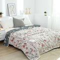  Soft cotton bird-patterned quilt draped over bed with gray pillows