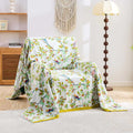  Birdsong cotton throw blanket with colorful birds and floral patterns draped on beige armchair in bright cozy room