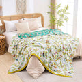 Soft Birdsong cotton throw blanket with vibrant bird and floral design spread over bed in natural light bedroom