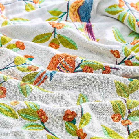  Close-up of birdsong cotton throw blanket showing colorful bird and floral embroidery on soft white cotton fabric