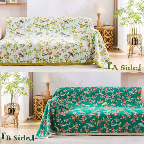  Reversible Birdsong cotton throw blanket with colorful bird and floral patterns draped on beige sofa, showing both sides in bright room