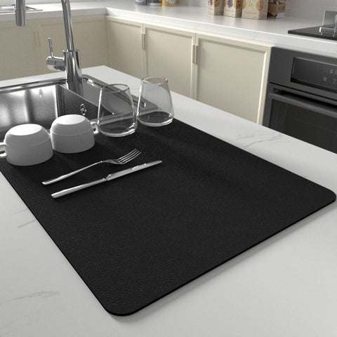 Black dish drying mat with mugs and cutlery next to sink