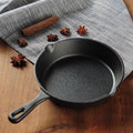 Cast iron skillet on a wooden surface with star anise and cinnamon sticks.