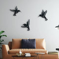 Black bird wall decorations on a white wall above a beige sofa.