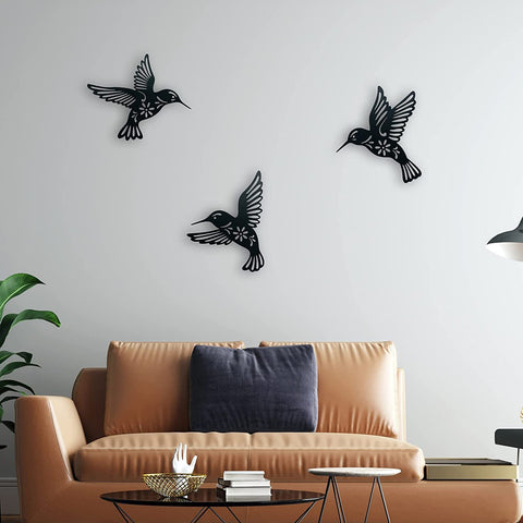Black bird wall decorations on a white wall above a beige sofa.