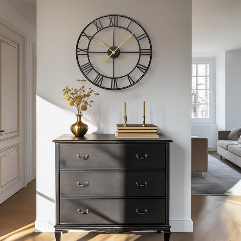 Black Roman numeral metal wall clock styled above vintage black dresser in hallway

