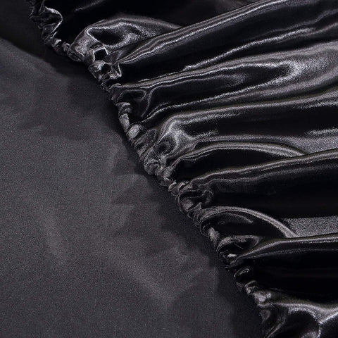 Close-up of elastic corner on luxury black satin fitted bed sheet