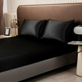 Black satin fitted sheet and silky pillowcases styled on king bed, perfect for luxury colorful bedding sets.