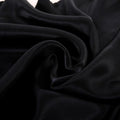 Ultra-soft black satin sheet fabric close-up showing smooth, glossy weave used in luxury colorful bedding
