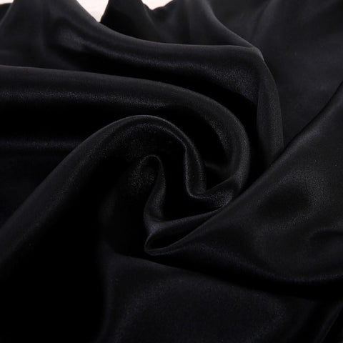 Ultra-soft black satin sheet fabric close-up showing smooth, glossy weave used in luxury colorful bedding