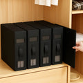 Set of black storage boxes with handles on a wooden shelf.