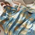 Woman resting under blue dandelion print reversible quilt – cozy and calming cotton throw