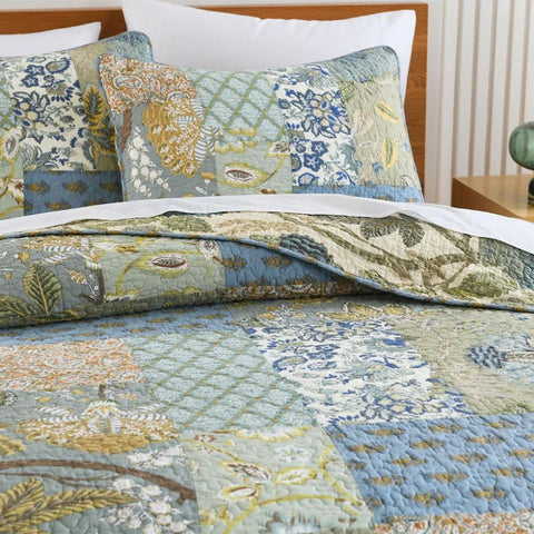 Blue and gold floral cotton quilt set on bed with rattan nightstand