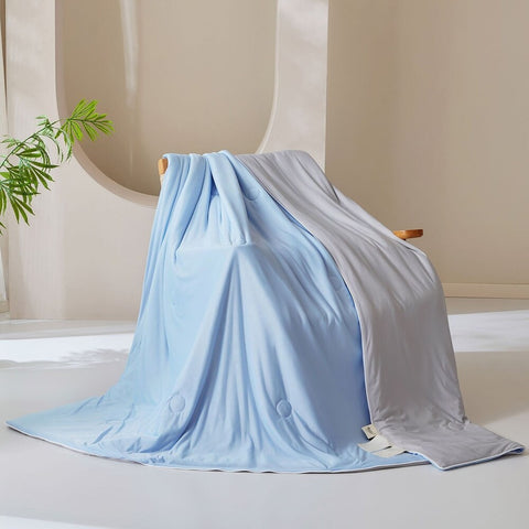 Light blue and gray double-layered ice silk quilt draped over modern chair in bright room