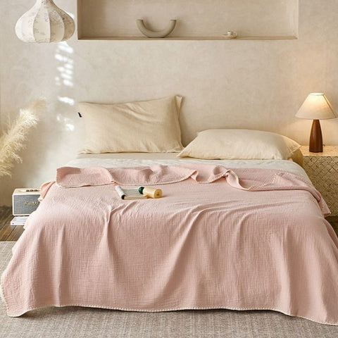  Blush pink cotton blanket with muslin texture and white trim on bed