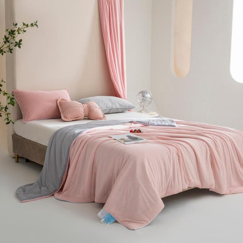 Blush pink cooling silk summer blanket draped over bed