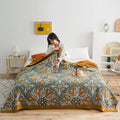 Woman holding boho cotton quilt on bed with orange floral pattern
