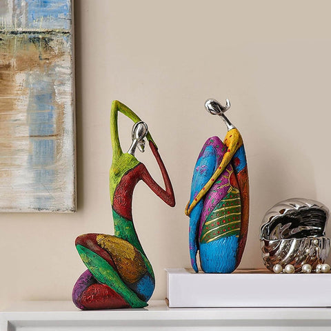 Colorful abstract sculptures on a shelf with a painting in the background