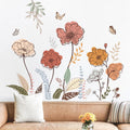 Floral wall decals on a white wall above a brown sofa with decorative pillows and a small table.