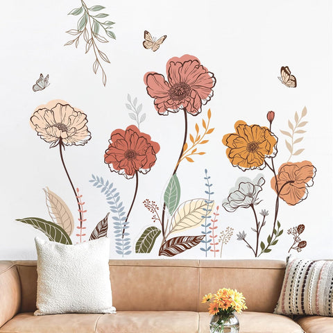 Floral wall decals on a white wall above a brown sofa with decorative pillows and a small table.