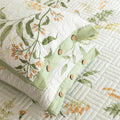 Quilt with floral patterns and green ribbon on a white background