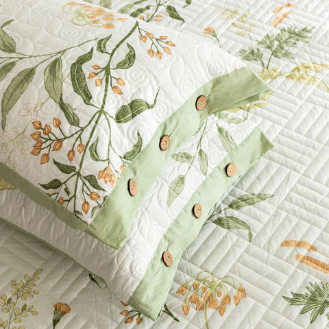Quilt with floral patterns and green ribbon on a white background