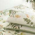 Botanical pillowcases stacked on bed with green trim
