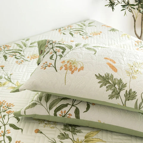 Botanical pillowcases stacked on bed with green trim