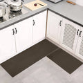 Brown kitchen mat on a gray floor in a kitchen setting with white cabinets and a cutting board.
