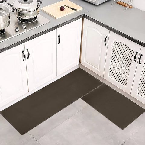 Brown kitchen mat on a gray floor in a kitchen setting with white cabinets and a cutting board.