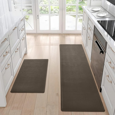 Two brown kitchen mats on a wooden floor with white cabinets and appliances in the background.