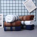Stack of folded towels in white, brown, and blue with decorative patterns on a grid background.