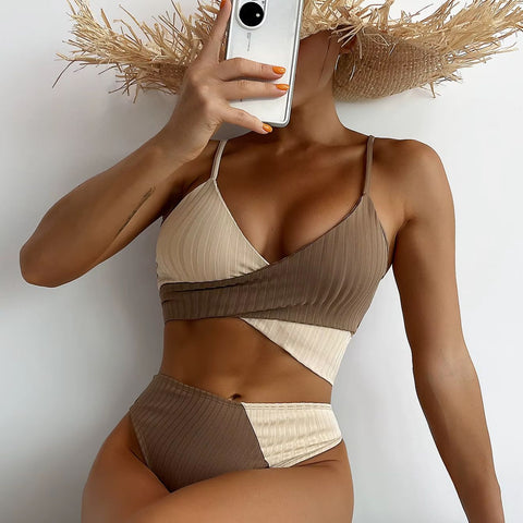 Woman in brown and beige ribbed bikini set posing with sunhat and phone, showing high-waisted bottom and cross-wrap top