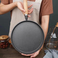 Woman holding round cast iron pan with wooden handle