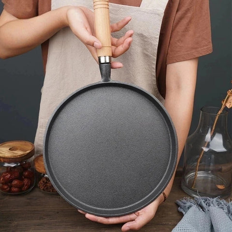 Woman holding round cast iron pan with wooden handle