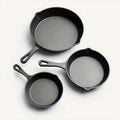 Three cast iron skillets of different sizes on a white background
