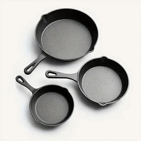Three cast iron skillets of different sizes on a white background