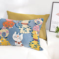 Single Cat Party cotton pillowcase with colorful playful cat illustrations on a blue background, placed on a white bed with a yellow cushion and framed wall art nearby.