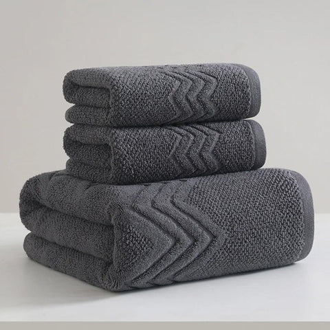 Stack of gray bath towels with textured pattern on a white surface