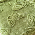 Close-up of plush butterfly pattern embossed on soft olive green throw blanket

