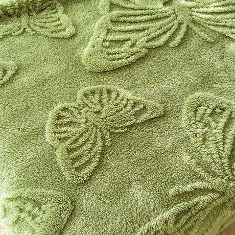 Close-up of plush butterfly pattern embossed on soft olive green throw blanket

