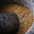 Close-up of ground spices inside black granite mortar with pestle